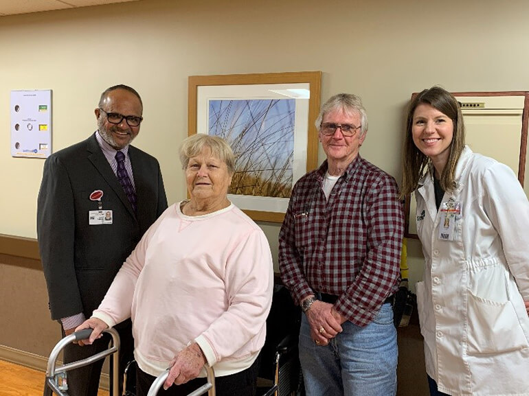 Dianna with her walker standing in hospital hallway with her husband, doctor and therapist.